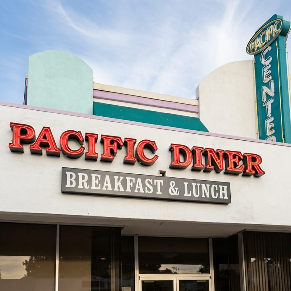 Pacific Diner restaurant facade with retro signage advertising breakfast and lunch under a bright blue sky.